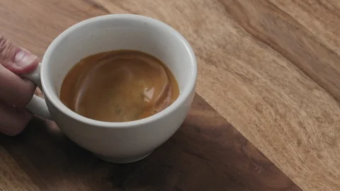 Slow motion handheld shot of swirl espresso in cappuccino cup from above Stock Footage 87681347