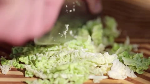 Slow motion of Hands Chopping Kale with a Kitchen Knife on a Wooden Board Video stock 306701258