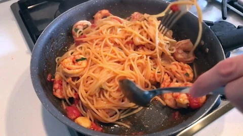 Slow motion of hands mixing in a pot pasta with tomatoes and big prawns. Stock-Footage 79854149