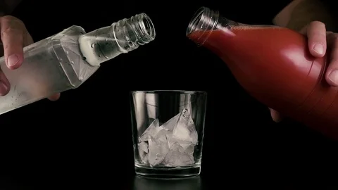 Slow motion. Hands simultaneously pour juice and vodka Stock Footage 76464765