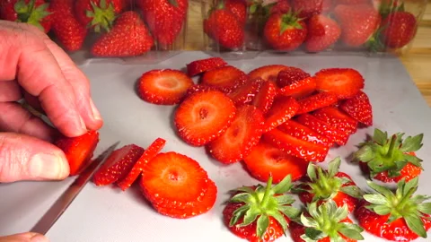 Slow motion - Hands slicing fresh strawberries on a chopping board. Stock Footage 200866335