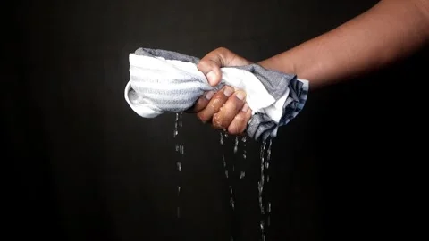 Slow motion of Hands squeeze wet towel against black background. draining water 動画素材 282498540