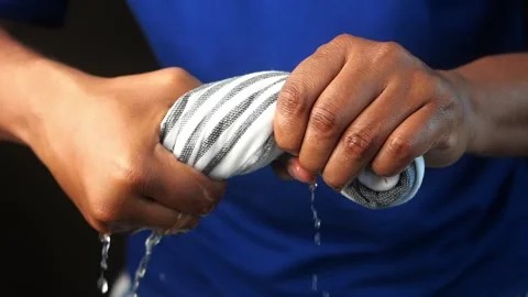 Slow motion of Hands squeeze wet towel against black background. Stock-Footage 297039464