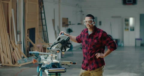 Slow motion of handsome carpenter wearing goggles, looking at the camera and Stock Footage 199621415