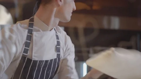 Slow motion of handsome pizza maker spinning and tossing pizza dough up Stock Footage 104854130