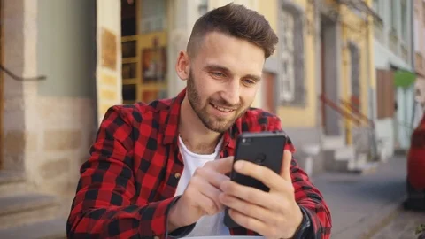 Slow motion handsome young man uses phone sitting in cafe smile happy blurred Stock Footage 92071028