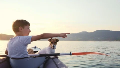 Slow motion of a happy boy with his dog Jack Russell paddling an kayak Stock Footage 96743010