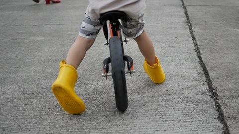 Slow motion happy boy playing balance bike on street road in the morning rain Stock Footage 113402394