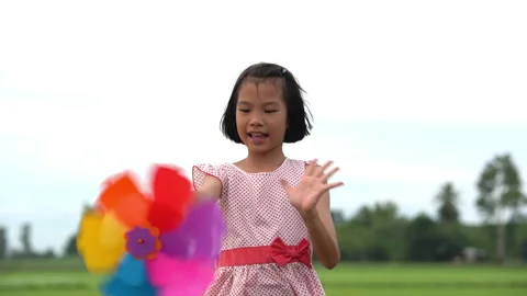 Slow motion happy children playing colorful pinwheel in meadow on sky background Stock Footage 158490257