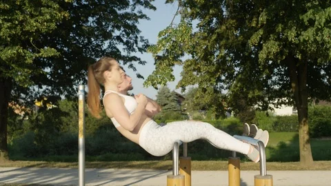 SLOW MOTION Happy couple working out together and doing sit ups on parallel bars Video stock 92529155