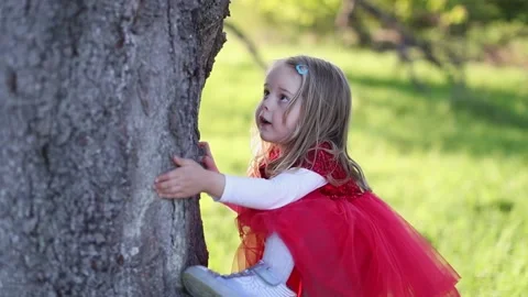 SLOW MOTION Happy cute blond little girl in red dress touch the tree Stock Footage 131780137