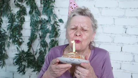 Slow motion. Happy smiling senior grandmother celebrate 85th birthday, holds Stock Footage 155695388