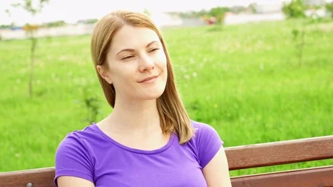 Slow Motion Happy Smiling Young Woman Enjoying Nature. Sitting on bench in green Stock Footage 77227031