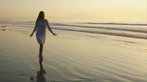 Slow motion of happy woman running on wet shore during sunset Stock Footage 59081789