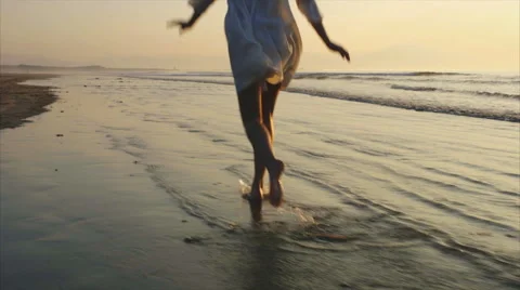 Slow motion of happy woman running on wet shore during sunset Stock Footage 59082250