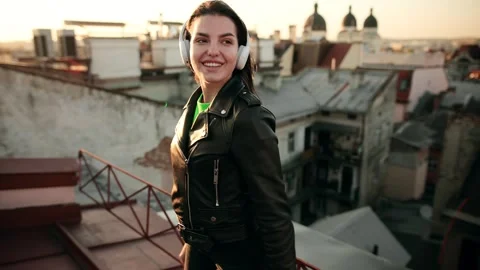 Slow motion of happy woman in wireless headphones dancing singing on a Roof at Stock Footage 312691653