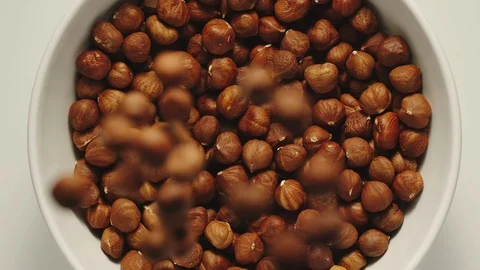 SLOW MOTION: Hazelnuts falling into a white bowl - Top View Vídeos de archivo 100430329
