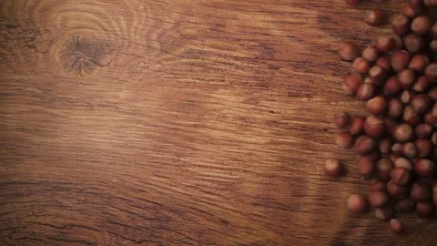 Slow motion hazelnuts in-shell rolling on a wooden table Stock Footage 73230463