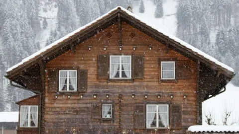 Slow motion of heavy snow falling down over wooden family house in Swiss Alps Stock Footage 129093465