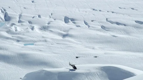Slow motion of helicopter picking up skiers from remote mountain area in Alaska Stock Footage 129110619