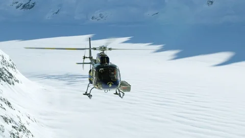 Slow motion of helicopter taking off from ice field up in mountains Stock Footage 129112054