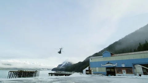 Slow motion of helicopter taking off from ski resort flying above hills Stock Footage 129110359