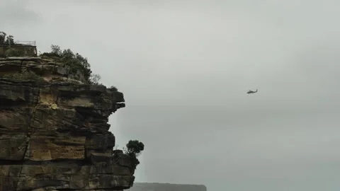 Slow motion helicoptor searching for body around the Gap in Sydney 4K Video stock 264987716