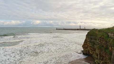 Slow motion high up footage of the waves rolling in to Whitby beach Video stock 287754301