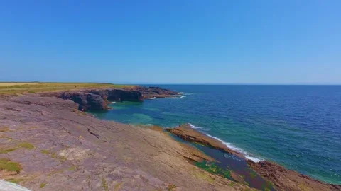 Slow motion high view of rocky headland extending into blue ocean water Stock Footage 340455797