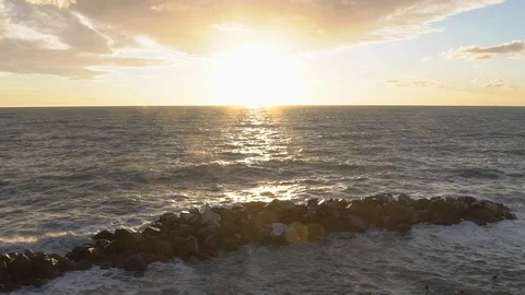 Slow motion - higher, jetty gets pounded by waves at sunset Stock Footage 103194303