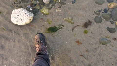 Slow motion hiking boots walking over rocks and water from point of view. Stock Footage 129658944
