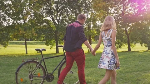 Slow motion of hipster couple walking together and riding a bike at sunset. Stockbeeldmateriaal 77238082