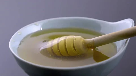 Slow motion honey dipper rolling in a  bowl of honey Stock Footage 55313450