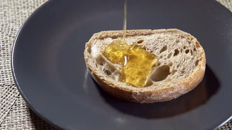 Slow motion. Honey flowing onto a slice of bread. Ciabatta bread. Stock Footage 295375237