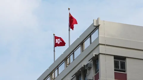 Slow motion of Hong Kong and China flags waving atop building under clear sky Stock Footage 307571257