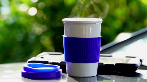 Slow motion. Hot ceramic white coffee cup with smoke placed outside the car Vídeos de archivo 253249647