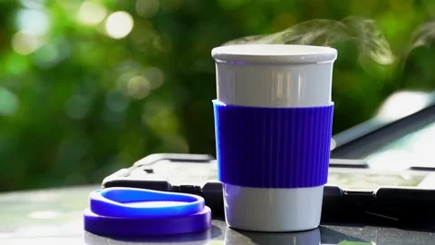 Slow motion. Hot ceramic white coffee cup with smoke placed outside the car.. Stockbeeldmateriaal 253250462