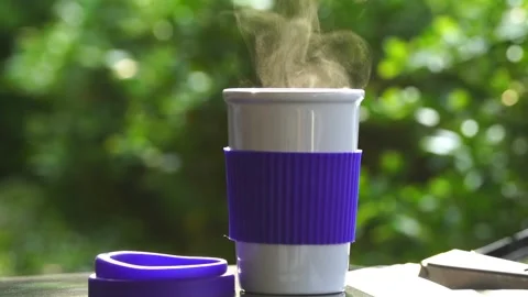 Slow motion. Hot ceramic white coffee cup with smoke placed outside the car Stockbeeldmateriaal 253251324