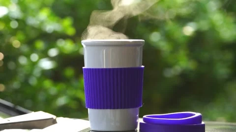 Slow motion. Hot ceramic white coffee cup with smoke placed outside the car.. Stockbeeldmateriaal 253251325