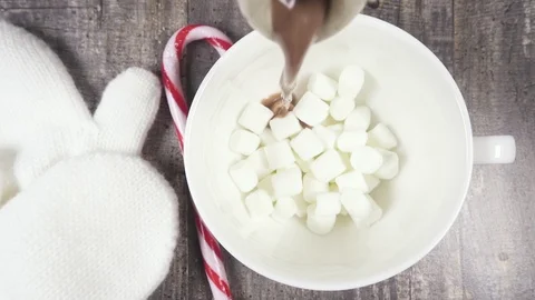 Slow motion hot chocolate pour into a mug of marshmallow top view Stock Footage 95850529