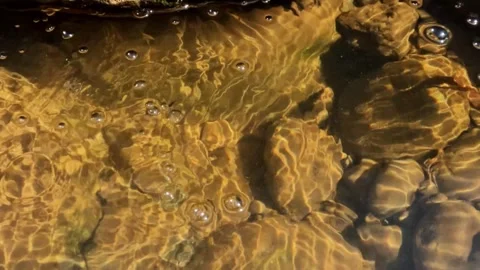 Slow motion hot water bubbles in a rocky river 動画素材 307432203