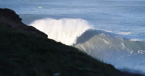 Slow motion of huge ocean waves swimming towards cliff with boat in background Stock Footage 155796630