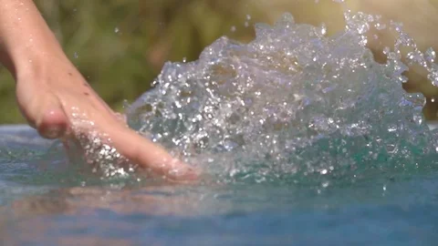 SLOW MOTION Human hand sliding through water surface splashing drops in pool Stock Footage