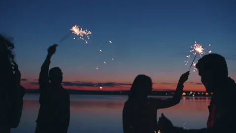 Slow motion of human silhouettes dancing at night beach party waving bengal Video stock 160729664