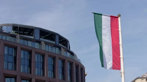 Slow motion of Hungarian flag with modern glass building background Stock Footage 313497419