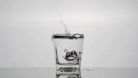 Slow-motion Ice Cube Drop into Crystal Clear Glass - White Background Stock Footage 240159316