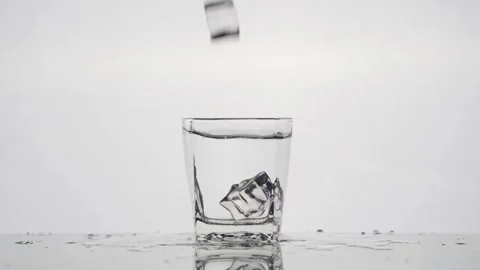 Slow-motion Ice Cube Drop into Crystal Clear Glass - White Background Stock Footage 240159548