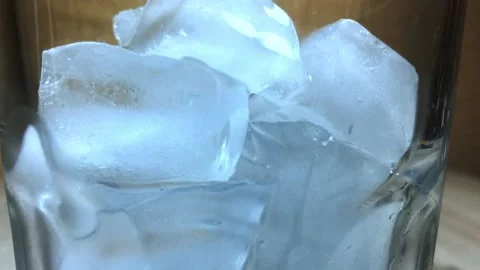 Slow motion ice cubes in glass with light blue water Video stock 157002632