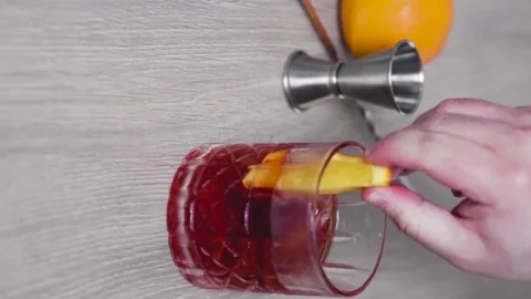 Slow motion of an ice-filled glass of negroni being stirred with a piece of o Stock Footage 156564720