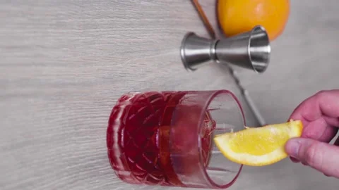 Slow motion of an ice-filled glass of negroni while dropping a piece of fresh Stock Footage 156564747